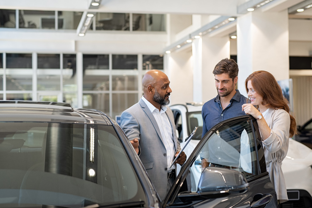 Couple-examining-new-auto-with-car-dealer